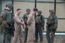 Staff Sgt. Joseph Pistone and Cpl. David Poirier, instructors of Close Quarters Battle Course 2-17, explain the importance of tying the hands of the possible threat behind their back as part of advanced clearing, aboard Naval Support Activity Northwest Annex, Chesapeake, Va., May 23. Proper restraining techniques was one of the many procedures taught during the advanced-clearing portion of the seven-week course. (U.S. Marine Corps photo by Cpl. Logan Snyder/ Released)