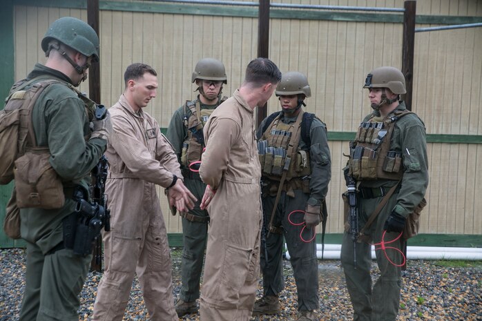 Staff Sgt. Joseph Pistone and Cpl. David Poirier, instructors of Close Quarters Battle Course 2-17, explain the importance of tying the hands of the possible threat behind their back as part of advanced clearing, aboard Naval Support Activity Northwest Annex, Chesapeake, Va., May 23. Proper restraining techniques was one of the many procedures taught during the advanced-clearing portion of the seven-week course. (U.S. Marine Corps photo by Cpl. Logan Snyder/ Released)