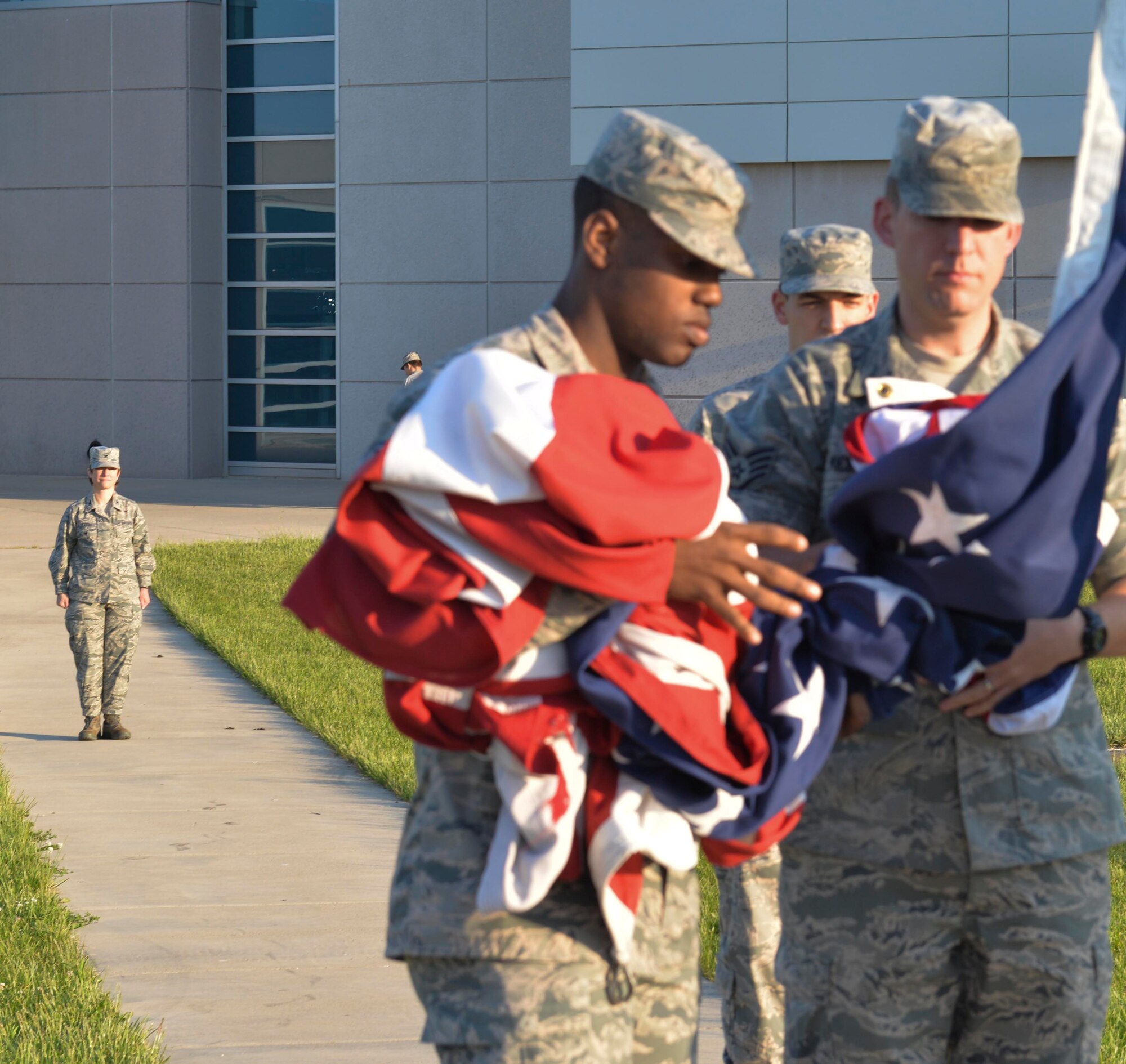 Wright-Patterson AFB, Ohio -- The NASIC color guard prepares the U.S. flag for reveille while Col. Trish Sexton, NASIC vice commander, watches here May 15. Sexton has carried the same U.S. flag from assignment to assignment throughout her career.  "It was given to me by the Airmen from my second assignment and had been flown over the headquarters of my first assignment " said Sexton. "It has been everywhere with me." The flag will be used in Sexton's retirement ceremony July 13.