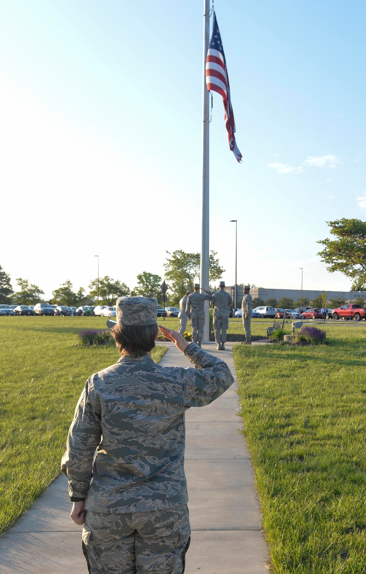 Wright-Patterson AFB, Ohio -- Col. Trish Sexton, NASIC vice commander, salutes while the NASIC color guard raise a U.S. flag during reveille here May 15. Sexton has carried the same U.S. flag from assignment to assignment throughout her career.  "It was given to me by the Airmen from my second assignment and had been flown over the headquarters of my first assignment " said Sexton. "It has been everywhere with me." The flag will be used in Sexton's retirement ceremony July 13.