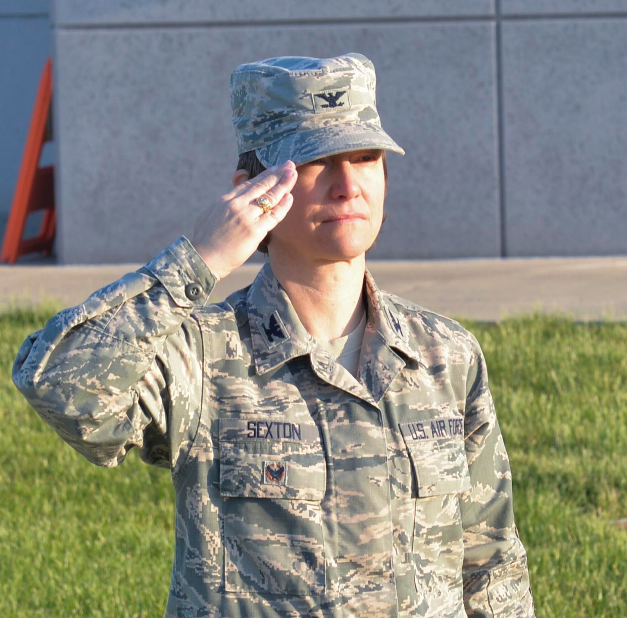 Wright-Patterson AFB, Ohio -- Col. Trish Sexton, NASIC vice commander, salutes a U.S. flag during reveille here May 15. Sexton has carried the same U.S. flag from assignment to assignment throughout her career.  "It was given to me by the Airmen from my second assignment and had been flown over the headquarters of my first assignment " said Sexton. "It has been everywhere with me." The flag will be used in Sexton's retirement ceremony July 13.