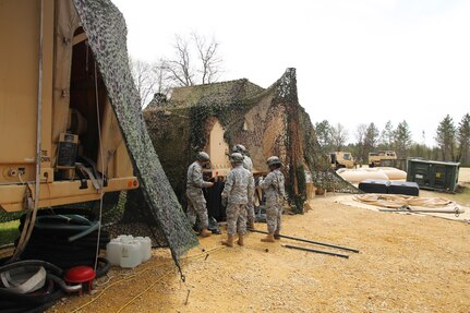 Soldiers with the 810th Quartermaster Company of Cincinnati, Ohio, reconfigure camouflage netting on a Reverse-Osmosis Water Purification Unit at Big Sandy Lake on May 10, 2017, during operations for the 86th Training Division’s Warrior Exercise 86-17-02 at Fort McCoy, Wis. The Warrior Exercise provides unique training opportunities for various Soldiers in various military occupation specialties to train together on simulated combat missions and to work together as a team, just like they would in a real-world environment. The 810th provided the majority of the drinkable water used in the exercise through water-purification efforts. (U.S. Army Photo by Scott T. Sturkol, Public Affairs Office, Fort McCoy, Wis.)