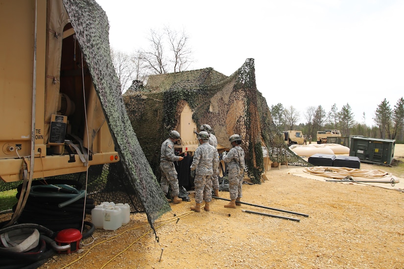 Soldiers with the 810th Quartermaster Company of Cincinnati, Ohio, reconfigure camouflage netting on a Reverse-Osmosis Water Purification Unit at Big Sandy Lake on May 10, 2017, during operations for the 86th Training Division’s Warrior Exercise 86-17-02 at Fort McCoy, Wis. The Warrior Exercise provides unique training opportunities for various Soldiers in various military occupation specialties to train together on simulated combat missions and to work together as a team, just like they would in a real-world environment. The 810th provided the majority of the drinkable water used in the exercise through water-purification efforts. (U.S. Army Photo by Scott T. Sturkol, Public Affairs Office, Fort McCoy, Wis.)