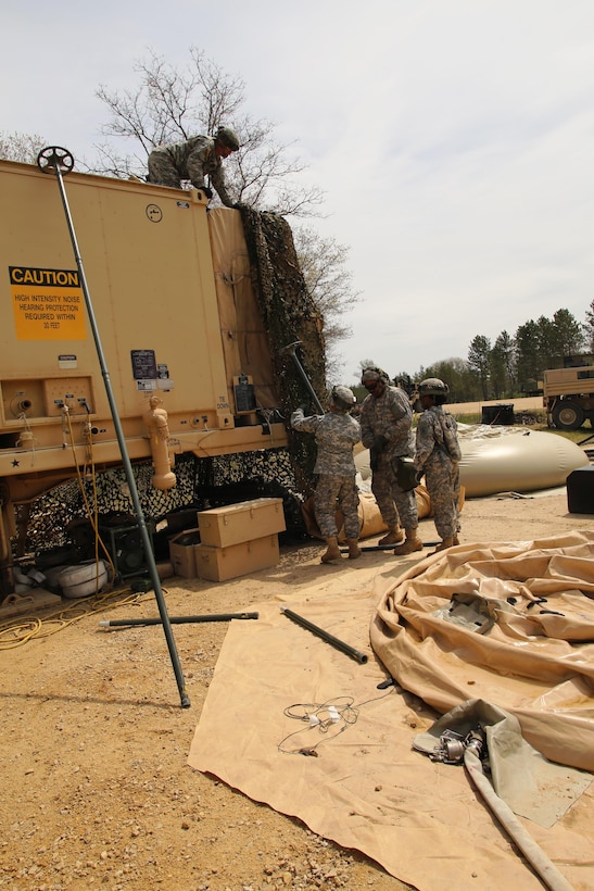Soldiers with the 810th Quartermaster Company of Cincinnati, Ohio, reconfigure camouflage netting on a Reverse-Osmosis Water Purification Unit at Big Sandy Lake on May 10, 2017, during operations for the 86th Training Division’s Warrior Exercise 86-17-02 at Fort McCoy, Wis. The Warrior Exercise provides unique training opportunities for various Soldiers in various military occupation specialties to train together on simulated combat missions and to work together as a team, just like they would in a real-world environment. The 810th provided the majority of the drinkable water used in the exercise through water-purification efforts. (U.S. Army Photo by Scott T. Sturkol, Public Affairs Office, Fort McCoy, Wis.)