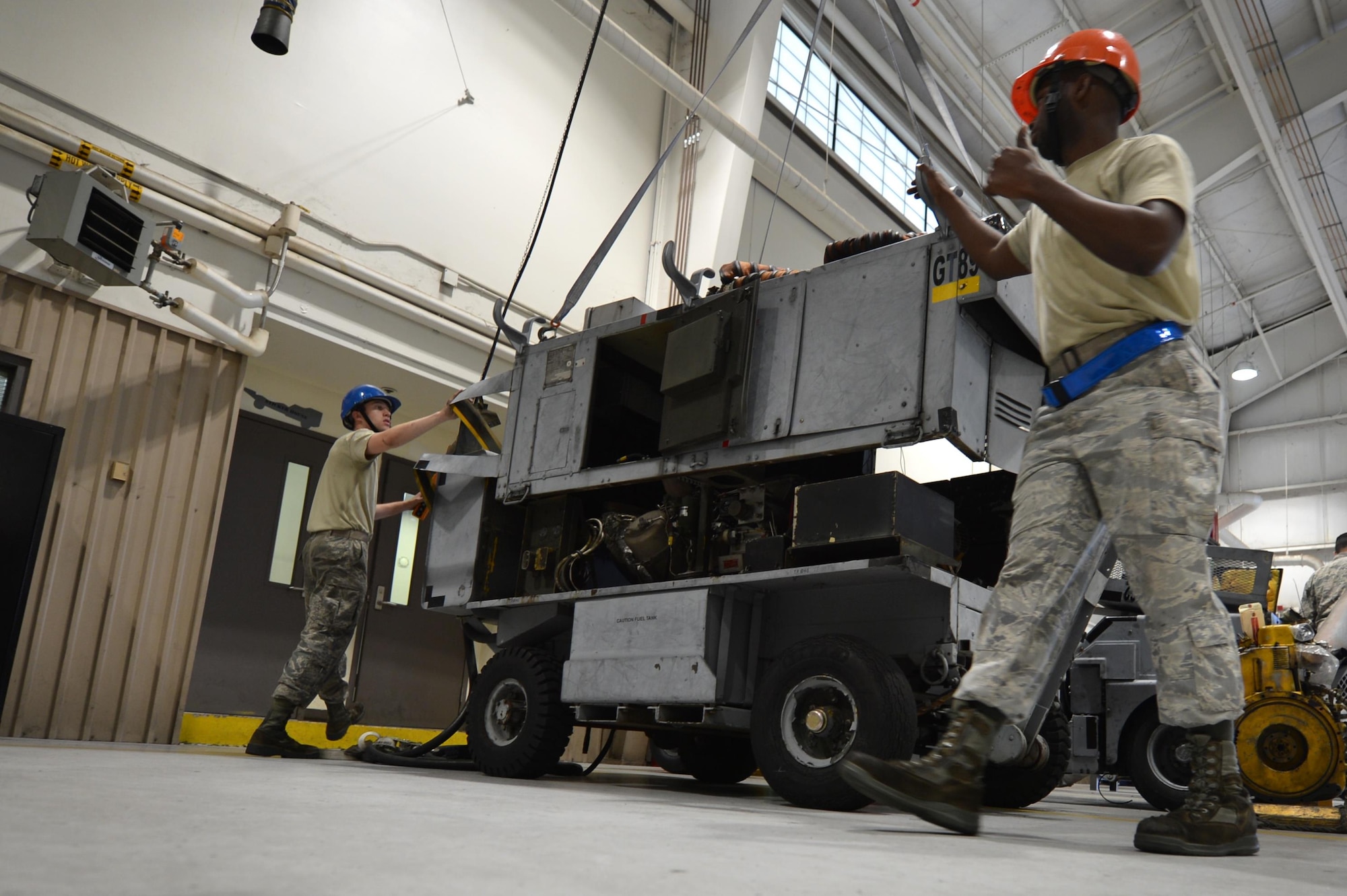 U.S. Airmen assigned to the 20th Equipment Maintenance Squadron aerospace ground equipment (AGE) flight use a lift to remove the top of an A/M32A-60 generator at Shaw Air Force Base, S.C., May 24, 2017. Airmen assigned to the AGE flight utilize an array of tools and machinery to perform repairs on any and all aircraft maintenance equipment that enters the work center. (U.S. Air Force photo by Airman 1st Class Christopher Maldonado)