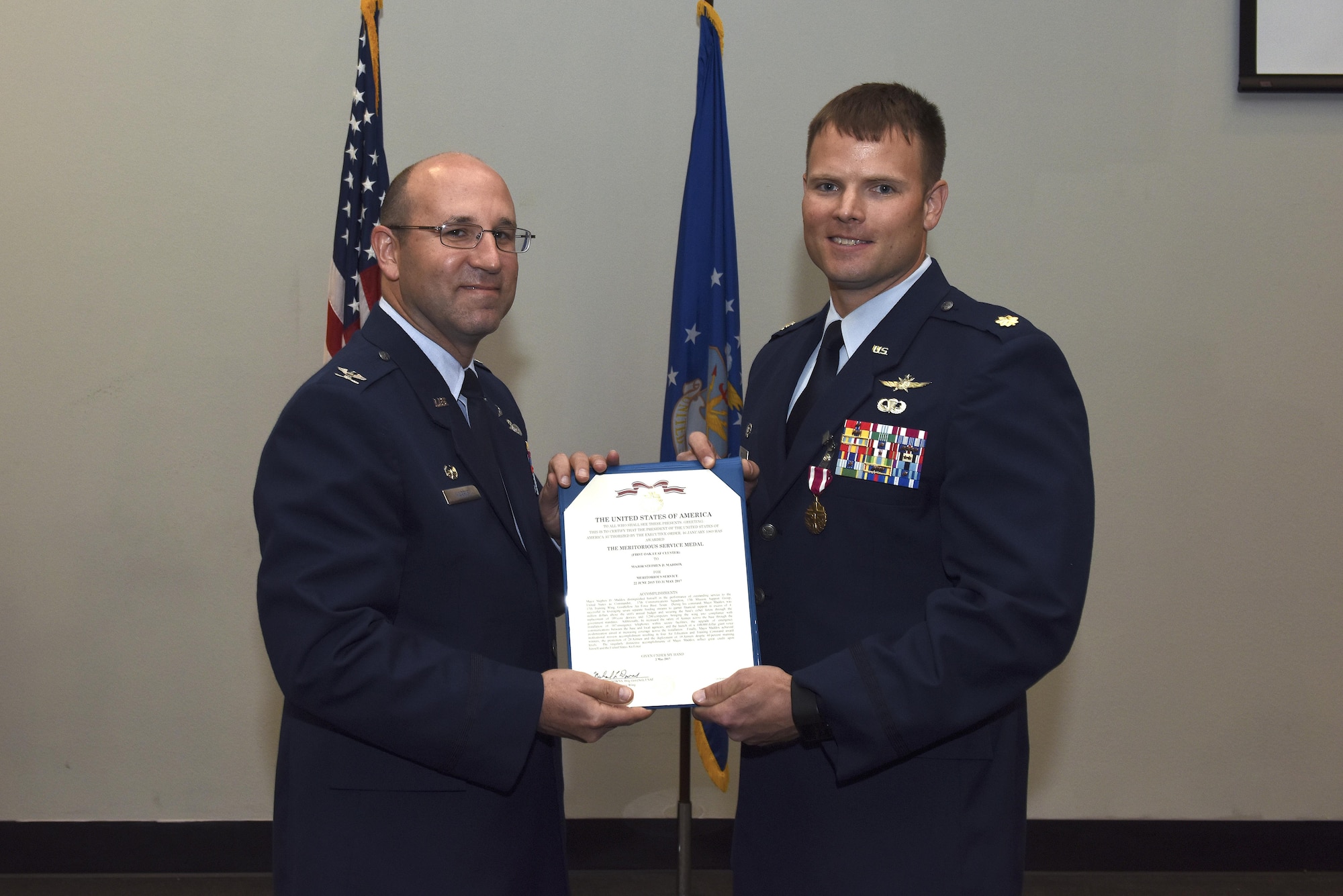 U.S. Air Force Col. Christopher Harris, 17th Mission Support Group commander, presents a Meritorious Service certificate to Maj. Stephen Maddox, 17th Communications Squadron commander, during the 17th CS change of command ceremony at the Event Center on Goodfellow Air Force Base, Texas, May 31, 2017. Maddox received the medal for outstanding service to his unit by providing new equipment and deployment opportunities for Airmen despite low manning.
