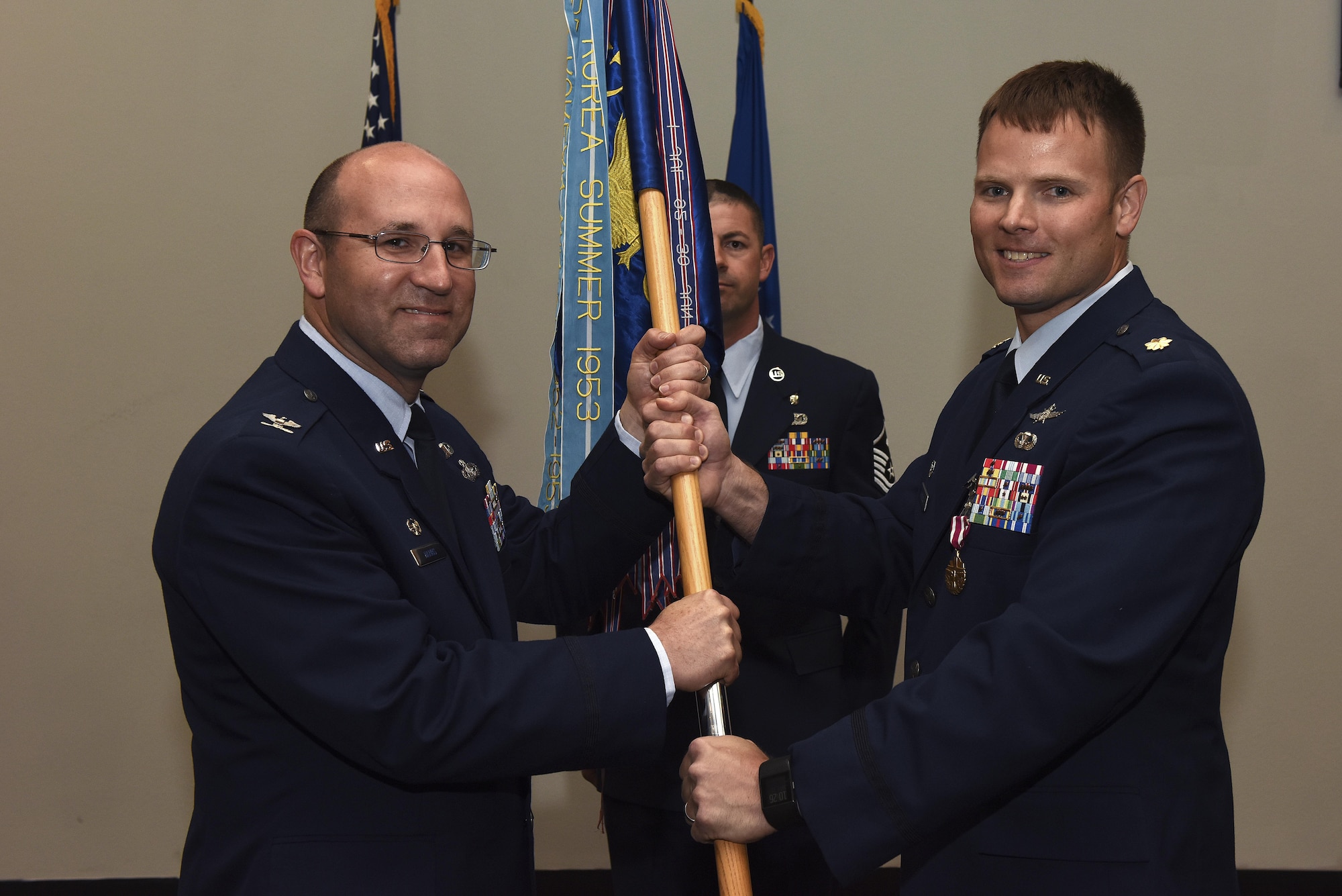 U.S. Air Force Col. Christopher Harris, 17th Mission Support Group commander, receives the unit guideon from Maj. Stephen Maddox, 17th Communications Squadron commander, during the 17th CS change of command ceremony at the Event Center on Goodfellow Air Force Base, Texas.
