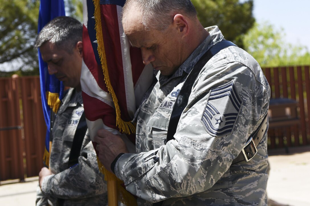 U.S. Air Force Chief Master Sgts. Raymond Mott, left, 7th Bomb Wing command chief, and Glen Pugh, 7th Maintenance Group superintendent, ensure flags are correctly positioned after placing them into stands. Both chiefs were taught by Dyess Honor Guardsmen how to perform a flag detail for Air Force ceremonies. (U.S. Air Force photo by Senior Airman Kedesha Pennant)