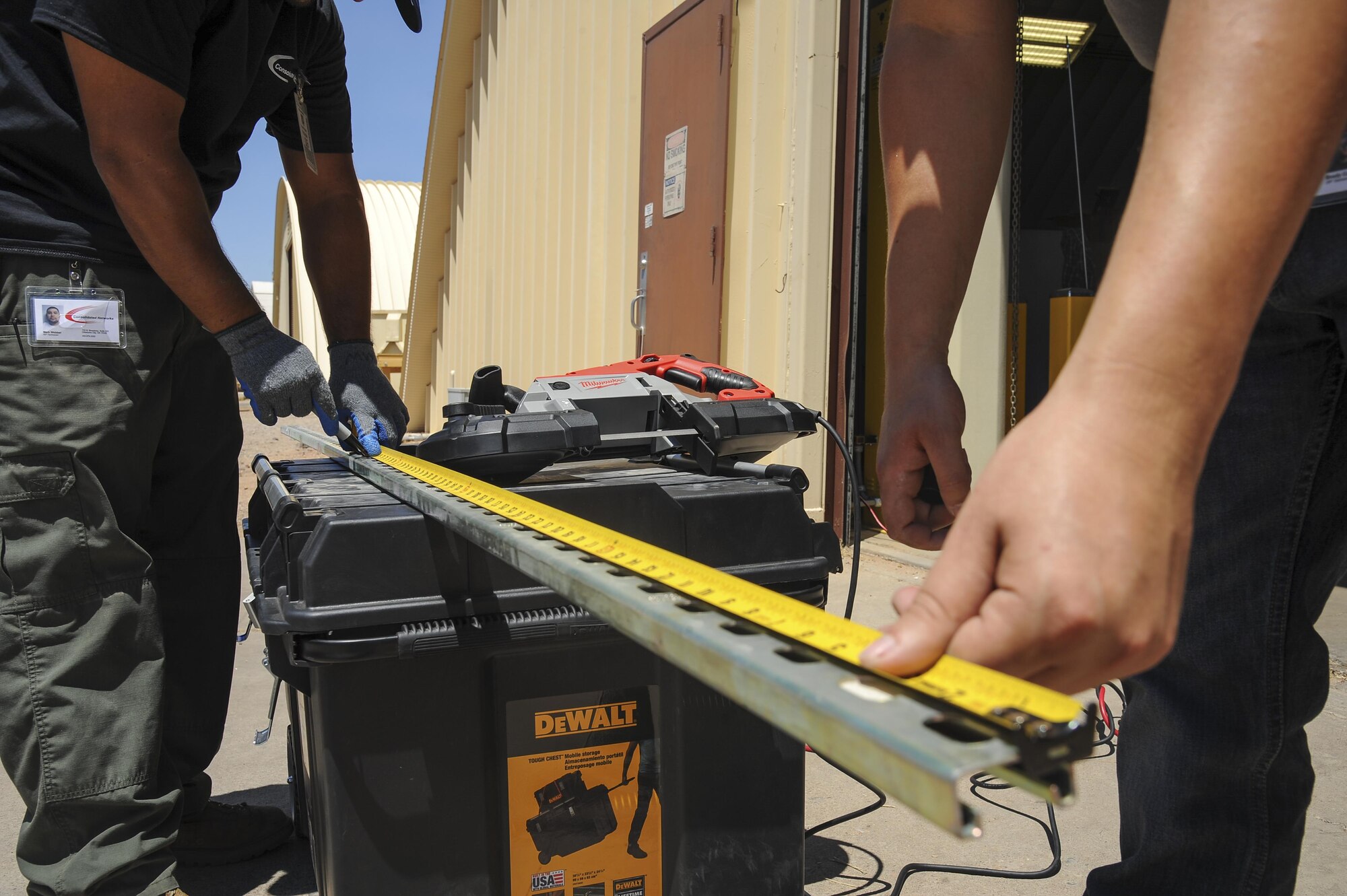 Brodie Carrier and Mark Webber, Consolidated Networks fiber technicians, take measurements for a bracket for a communications cabinet installation at the 309th Aircraft Maintenance and Regeneration Group at Davis-Monthan Air Force Base, Ariz., May 24, 2017. The fiber technicians can reinstall up to two communications cabinets in a day. (U.S. Air Force photo by Senior Airman Mya M. Crosby)