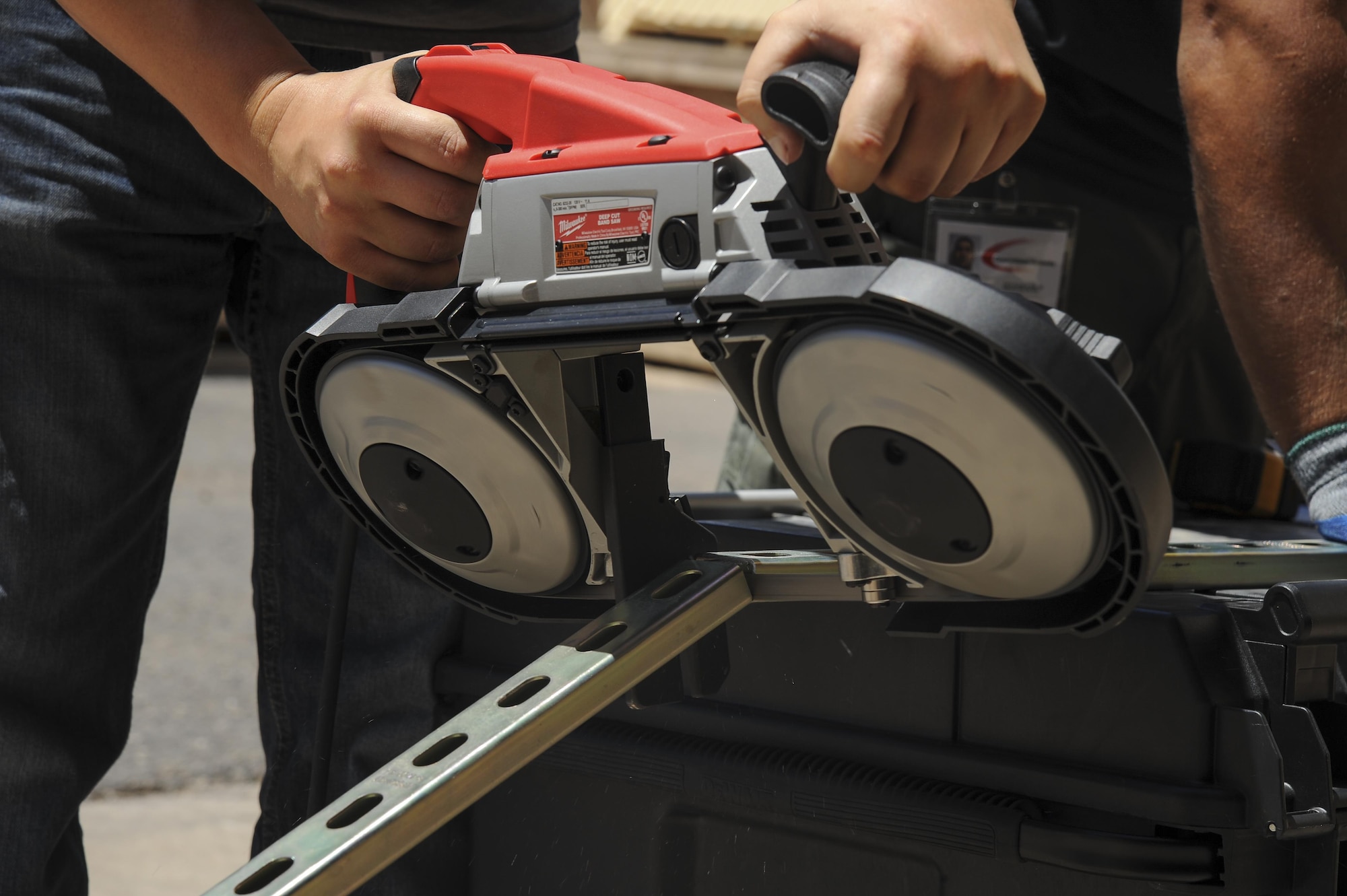 Brodie Carrier and Mark Webber, Consolidated Networks fiber technicians, use a band saw to cut a bracket for a communications cabinet installation at the 309th Aircraft Maintenance and Regeneration Group at Davis-Monthan Air Force Base, Ariz., May 24, 2017. The fiber technicians can reinstall up to two communications cabinets in a day. (U.S. Air Force photo by Senior Airman Mya M. Crosby)