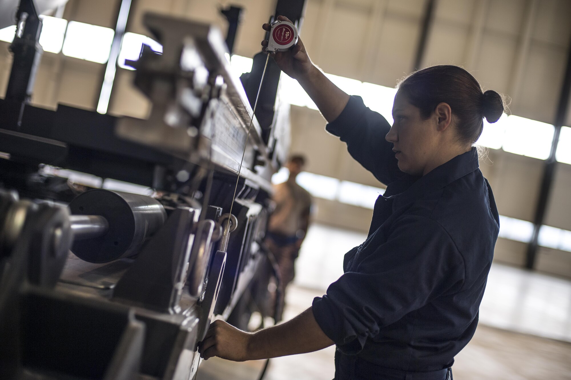 U.S. Air Force Staff Sgt. Jessica Tharp, 721st Aircraft Maintenance Squadron aerospace propulsion craftsman, measures the height of an engine transportation trailer before swapping out a C-17 Globemaster III engine in a hangar on Ramstein Air Base, Germany, Oct. 27, 2017. Tharp had to ensure the transportation trailer matched the height of an engine lift trailer so she could transfer the cradle over. The cradle allows the maintenance crew to safely lower the engine from the aircraft. (U.S. Air Force photo by Senior Airman Devin Boyer)