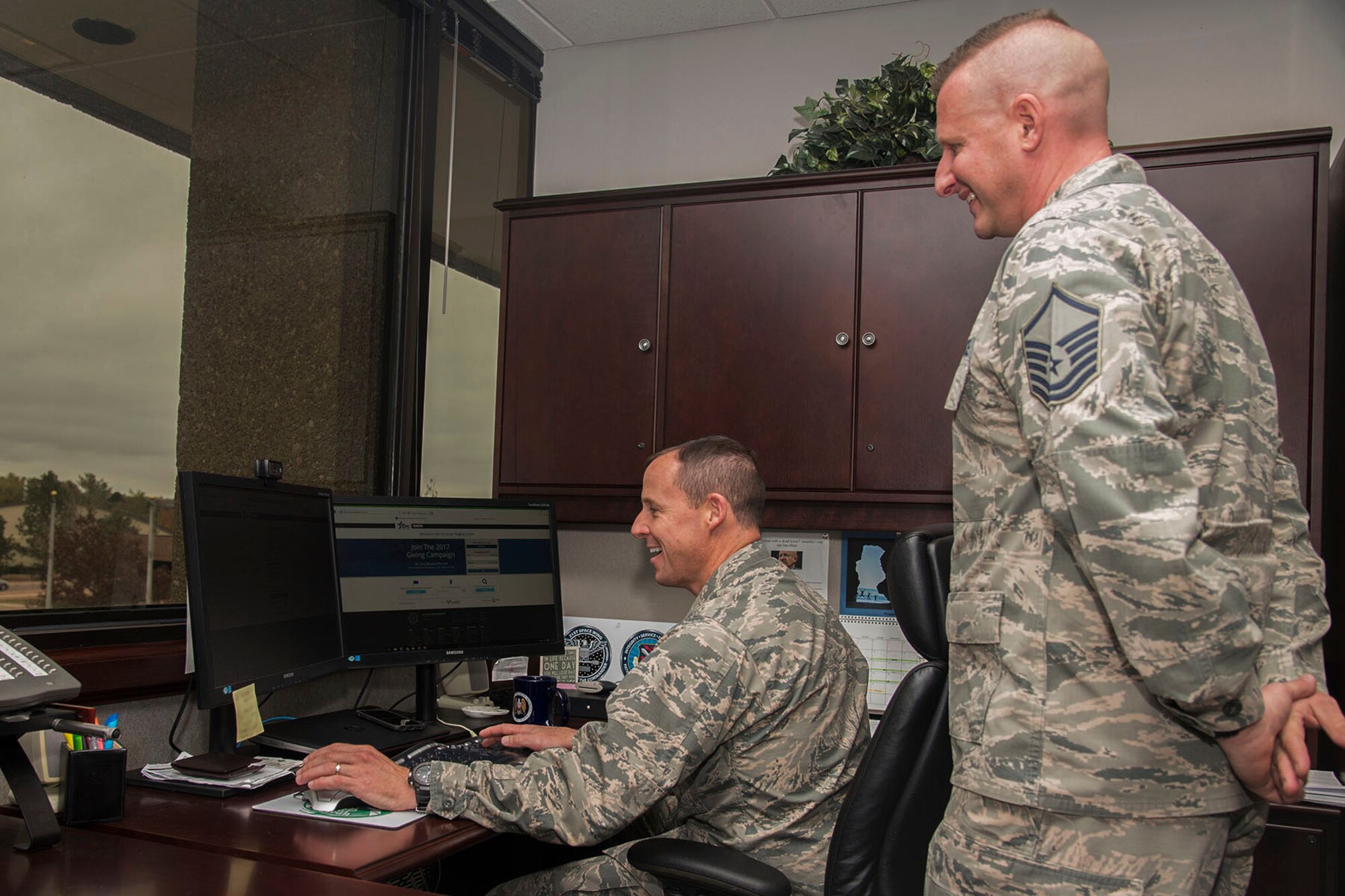 Master Sgt. Jason Gregory, 21st Civil Engineer Squadron noncommissioned officer in charge of requisitions and optimization, and installation project officer for the Combined Federal Campaign, assists Col. Todd Moore, 21st Space Wing commander, in making his commitment to CFC online, Oct. 30, 2017 at Peterson Air Force Base, Colorado.
On Peterson AFB the campaign kicks-off Nov. 6, 2017. Gregory said the goal is to have 100 percent contact with the squadrons on base, presenting Team Pete Airmen with the opportunity to participate in the campaign. CFC is an annual workplace charity campaign that allows contributors to elect to automatically give to groups from a broad range of charities and have it deducted directly from their paycheck. (U.S. Air Force photo by Staff Sgt. Tiffany Lundberg)