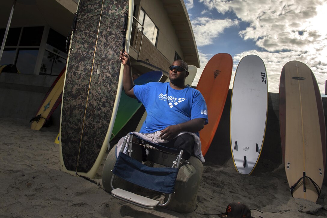 A double amputee surfer poses with his surfboard.