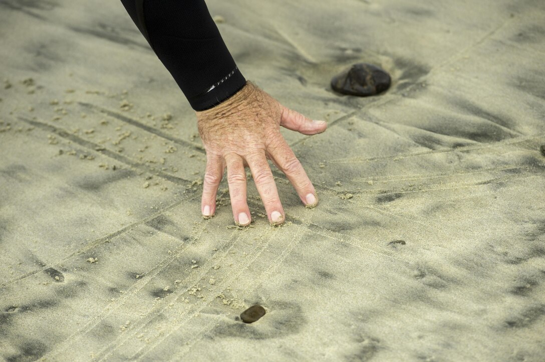 A surfing instructor draws a diagram in the sand.