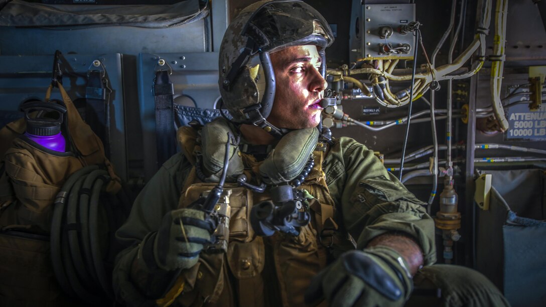 A Marine looks out the window of an aircraft.