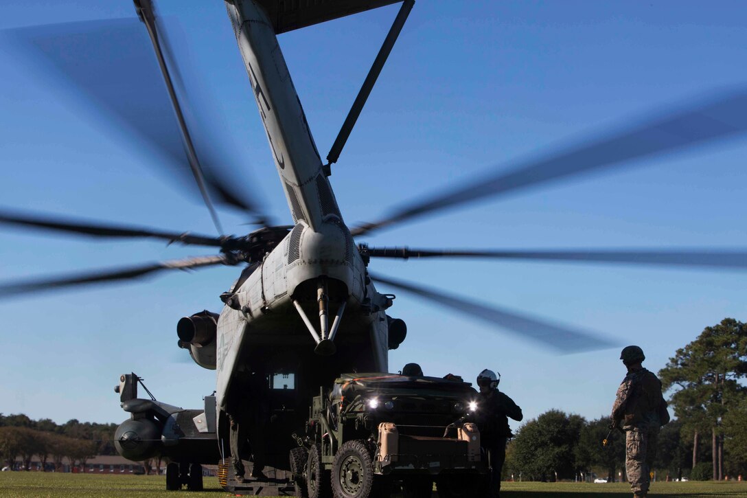 Marines load a vehicle into a helicopter.