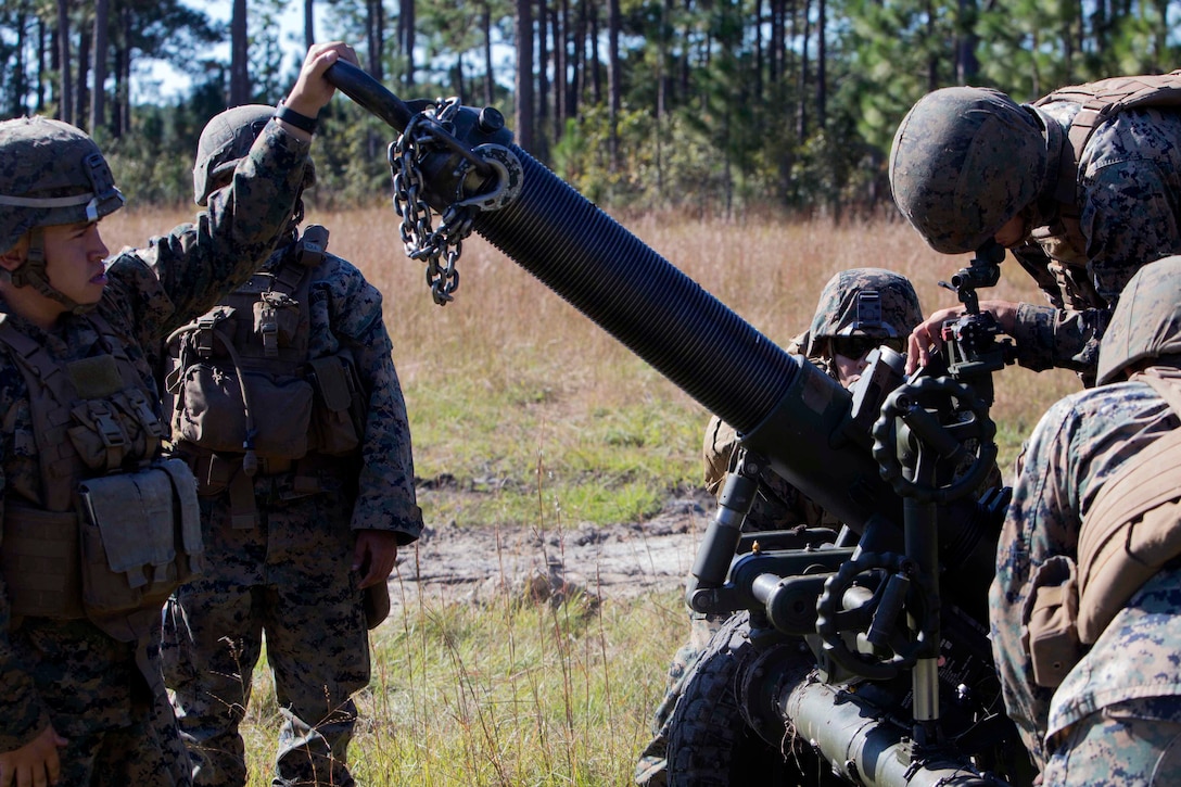 A marine looks though a sight on a mortar.