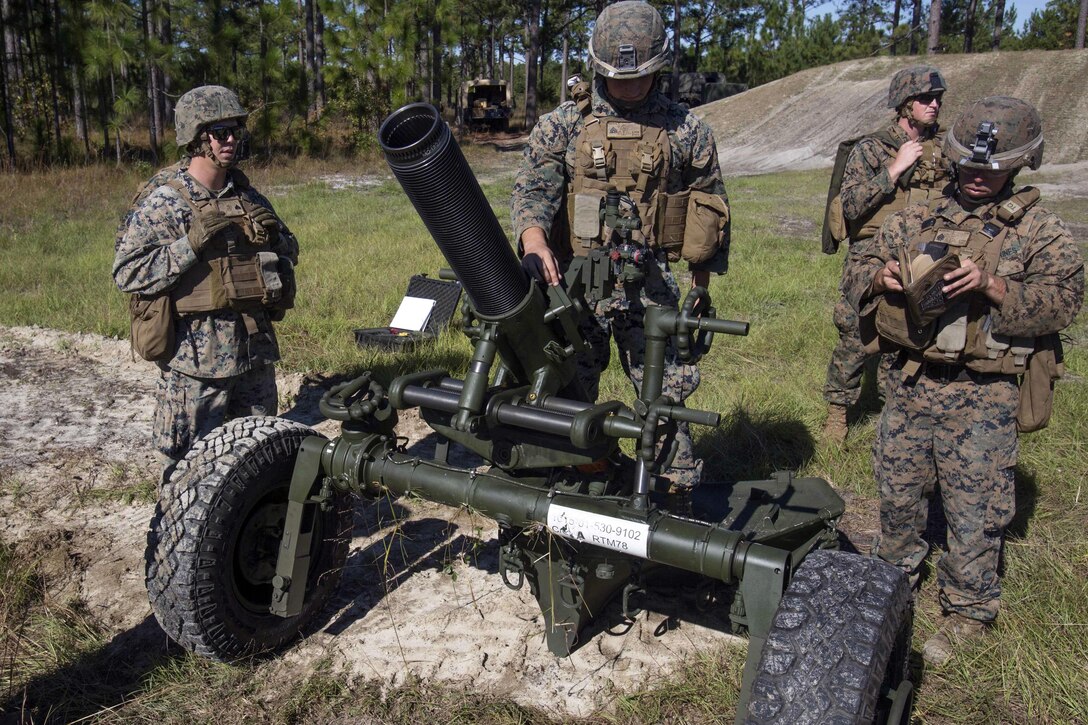 Four Marines gather behind a mortar to fire.