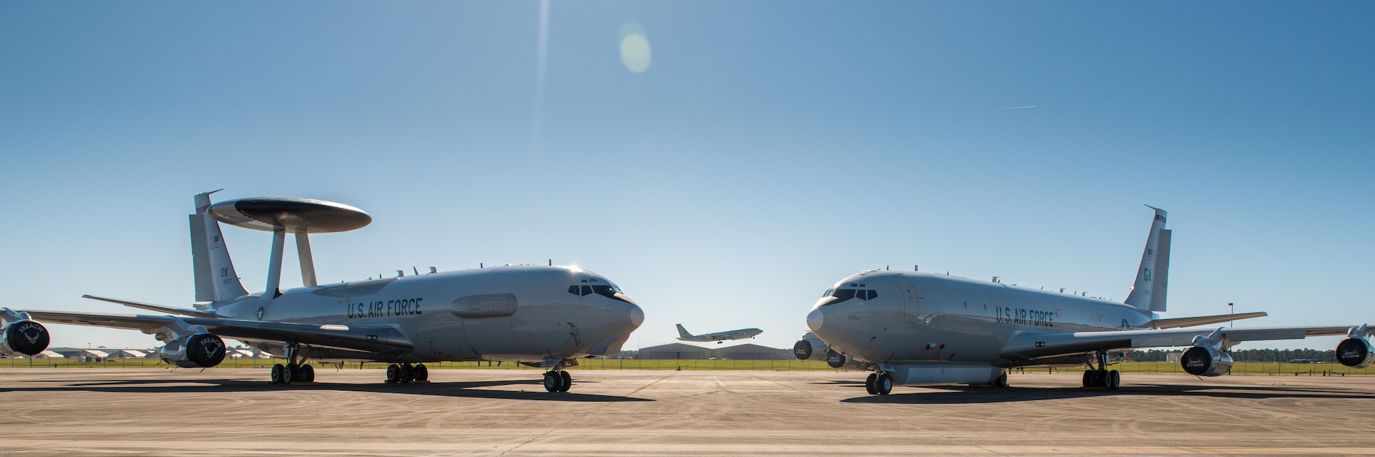 An E-3 Sentry AWACS from the 964th Airborne Air Control Squadron (AACS), 552nd Air Control Wing (ACW), Tinker Air Force Base (AFB), Oklahoma, sits on the flightline next to an E-8C Joint STARS from Team JSTARS as an E-8C Joint STARS aircraft passes in the background at Robins AFB, Ga, Oct. 26, 2017.