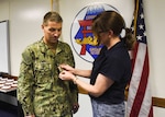 Samantha Correll places the rank of rear admiral upper half on Rear Adm. Richard Correll, commander, Submarine Group 7 (COMSUBGRU 7). COMSUBGRU 7 is comprised of submarines deployed to the Western Pacific and the Middle East; two forward-deployed submarine tenders and four attack submarines homeported in Guam; five surveillance towed array sensor system vessels and three oceanographic survey vessels when tasked for Theater Anti-Submarine Warfare operations.