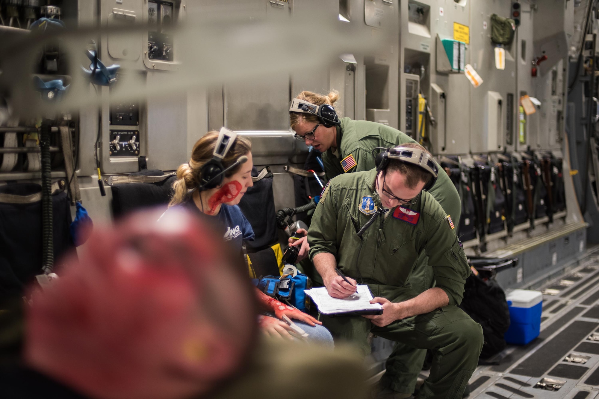 Staff Sgt. Avery Keller, an aeromedical evacuation technician from the 137th Aeromedical Evacuation Squadron, Will Rogers Air National Guard Base, Oklahoma City, completes medical documentation for a simulated burn patient, Senior Airman Ashleigh Duncan from the 137th Special Operations Logistics Readiness Squadron, while transporting patients with burn moulage aboard a C-17 Globemaster III from the 105th Airlift Wing, Stewart Air National Guard Base, N.Y., en route to Altus Air Force Base, Altus, Okla., Oct. 30, 2017. The flight was part of a wildfire scenario during Vigilant Guard, a North American Command-sponsored, state-wide emergency response exercise held Oct. 30 to Nov. 2, 2017. (U.S. Air National Guard photo by Staff Sgt. Kasey M. Phipps)