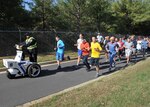 A group, several in costumes, run down a road