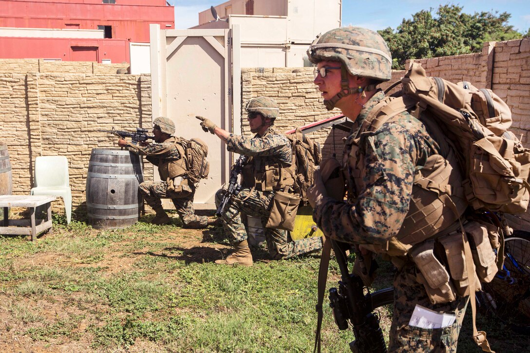 Marine Corps Lance Cpl. Travis Catero, center, points out an objective during Exercise Bougainville II at Landing Zone Boondocker, Marine Corps Base Hawaii.