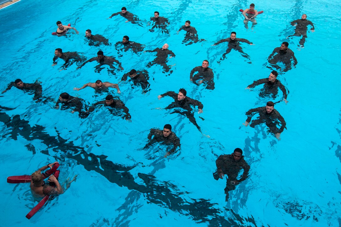 Lines of Marines tread water in a pool.