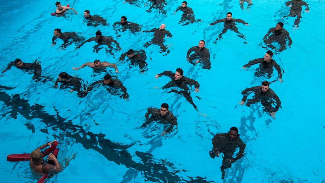 Lines of Marines tread water in a pool.