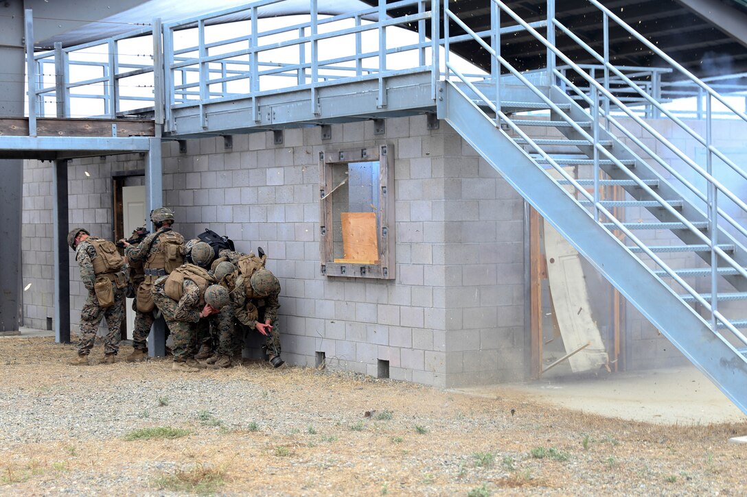 Marines take cover while conducting an urban breaching demolition exercise.