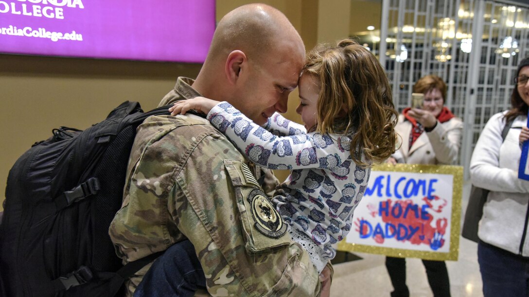An airman holds and hugs a child.