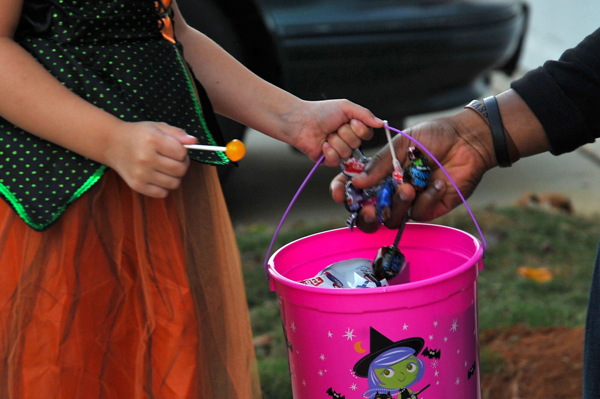 A base resident places candy in a child’s bucket during trick-or-treating at Shaw Air Force Base, South Carolina, Oct. 31, 2017.