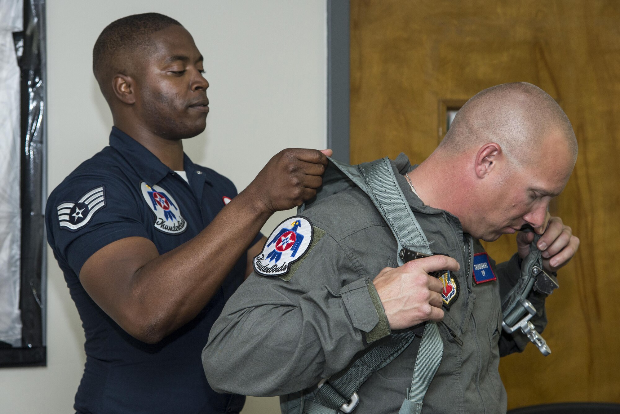 Staff Sgt. Jasper Roberts, U.S. Air Force Aerial Demonstration Squadron “Thunderbirds” aircrew flight equipment craftsman, helps Air Force Master Sgt. Benjamin Seekell, 343rd Training Squadron security forces apprentice course flight chief and Air Force Wounded Warrior, don a flight suite Nov. 2, 2017, at Joint Base San Antonio-Kelly Field, Texas.  Seekell was selected to fly with the Thunderbirds before they headline the 2017 Joint Base San Antonio Air Show and Open House Nov. 4-5. (U.S. Air Force photo by Senior Airman Stormy Archer)
