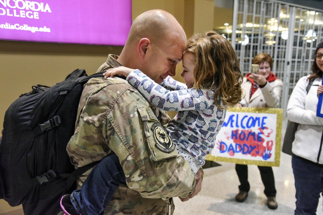 An airman holds and hugs a child.