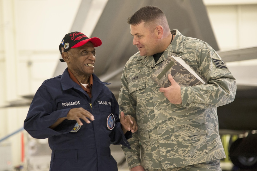 Two men have a conversation in front of a plane.