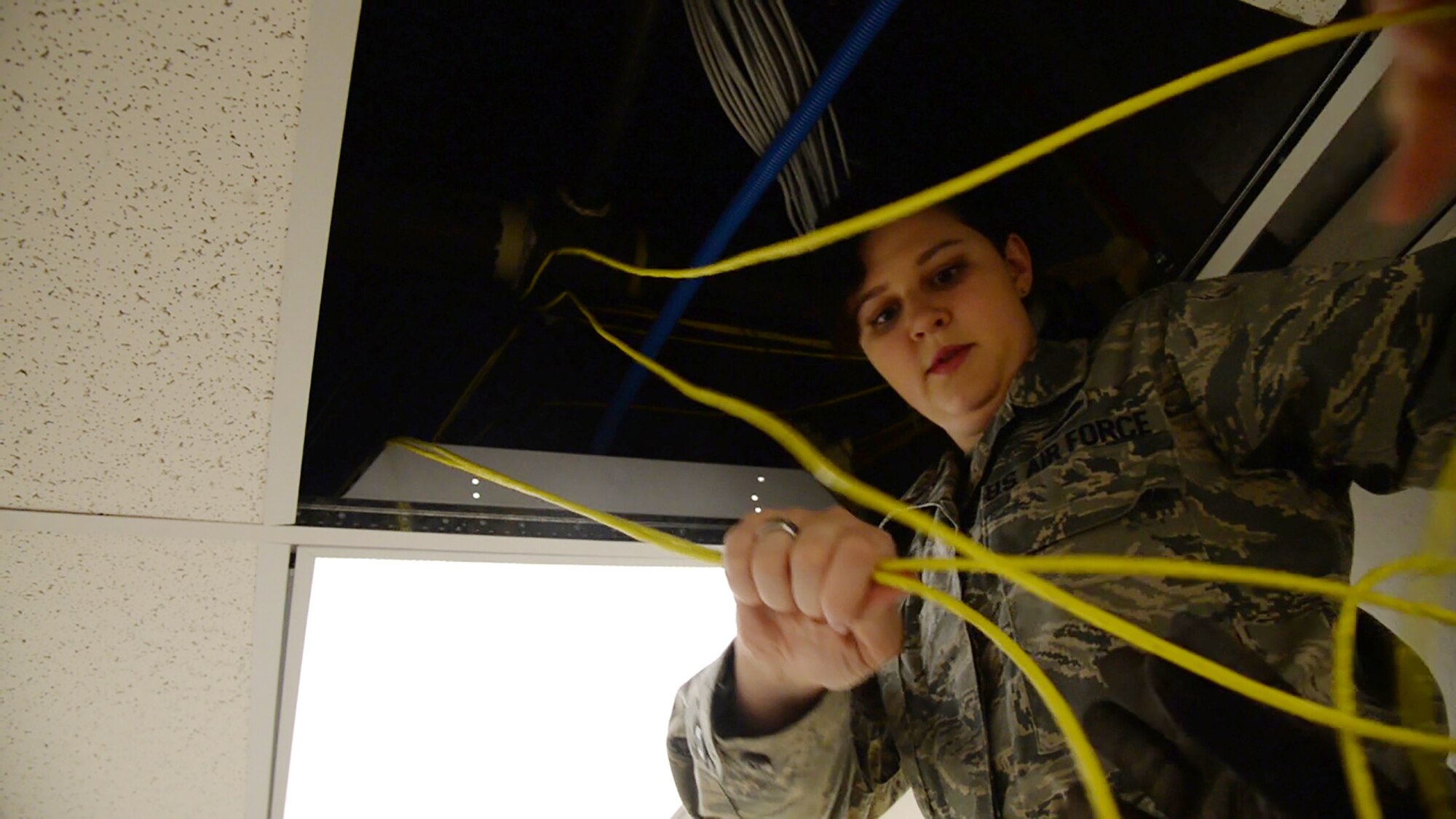 Senior Airman Margaret Merkling, 819th RED HORSE Squadron knowledge operator, pulls communication wires from a ceiling Oct. 31, 2017, at Malmstrom Air Force Base, Mont.