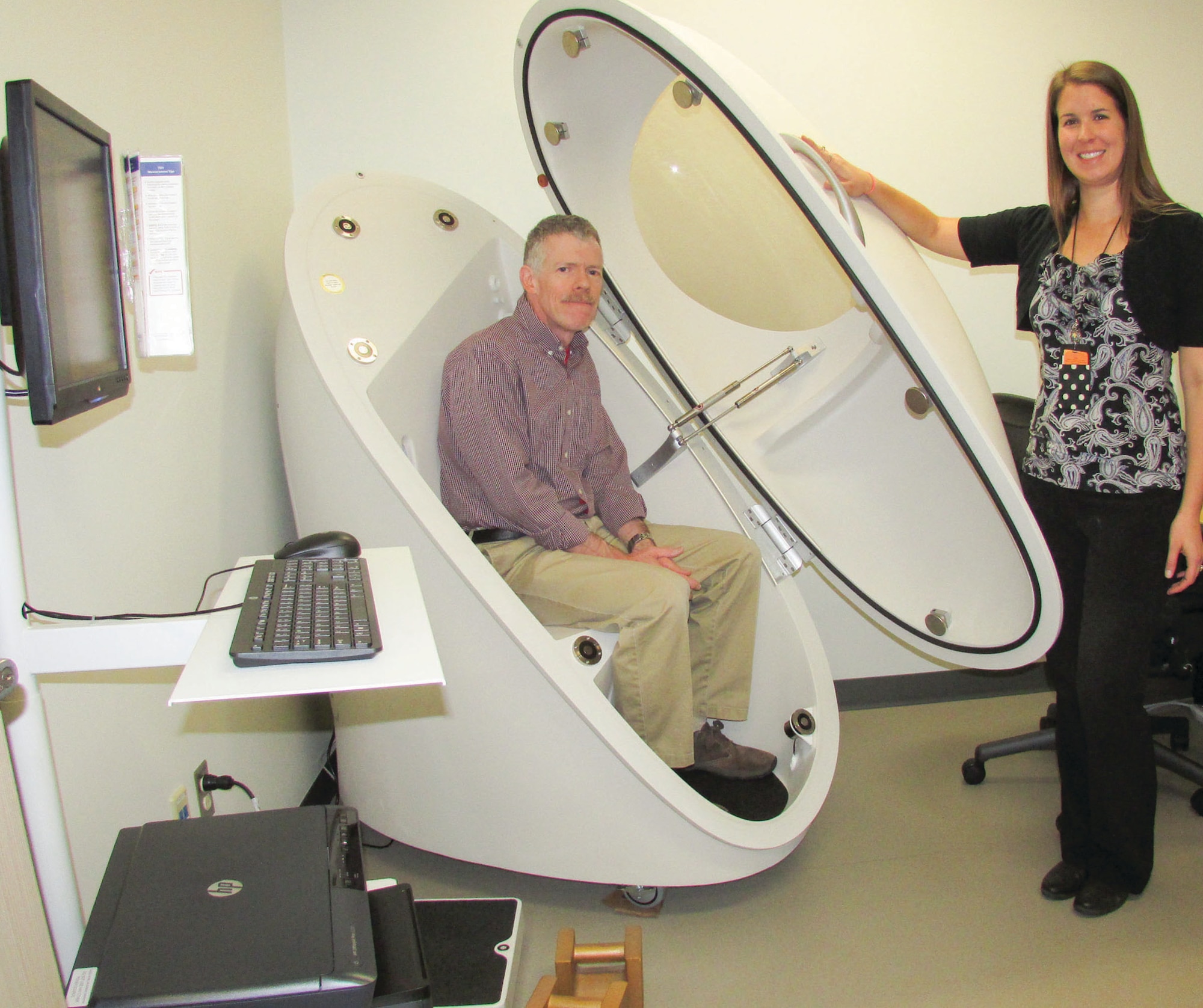 Guy Leahy and Kirsten David of the Health Promotions Flight show off the new Bod Pod at the 377th Medical Group building. The machine measures percentage of body fat and has several features the older Bod Pod didn’t.