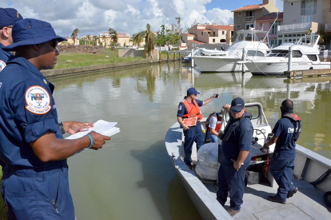 Members of the Coast Guard on land and on a boat talk.