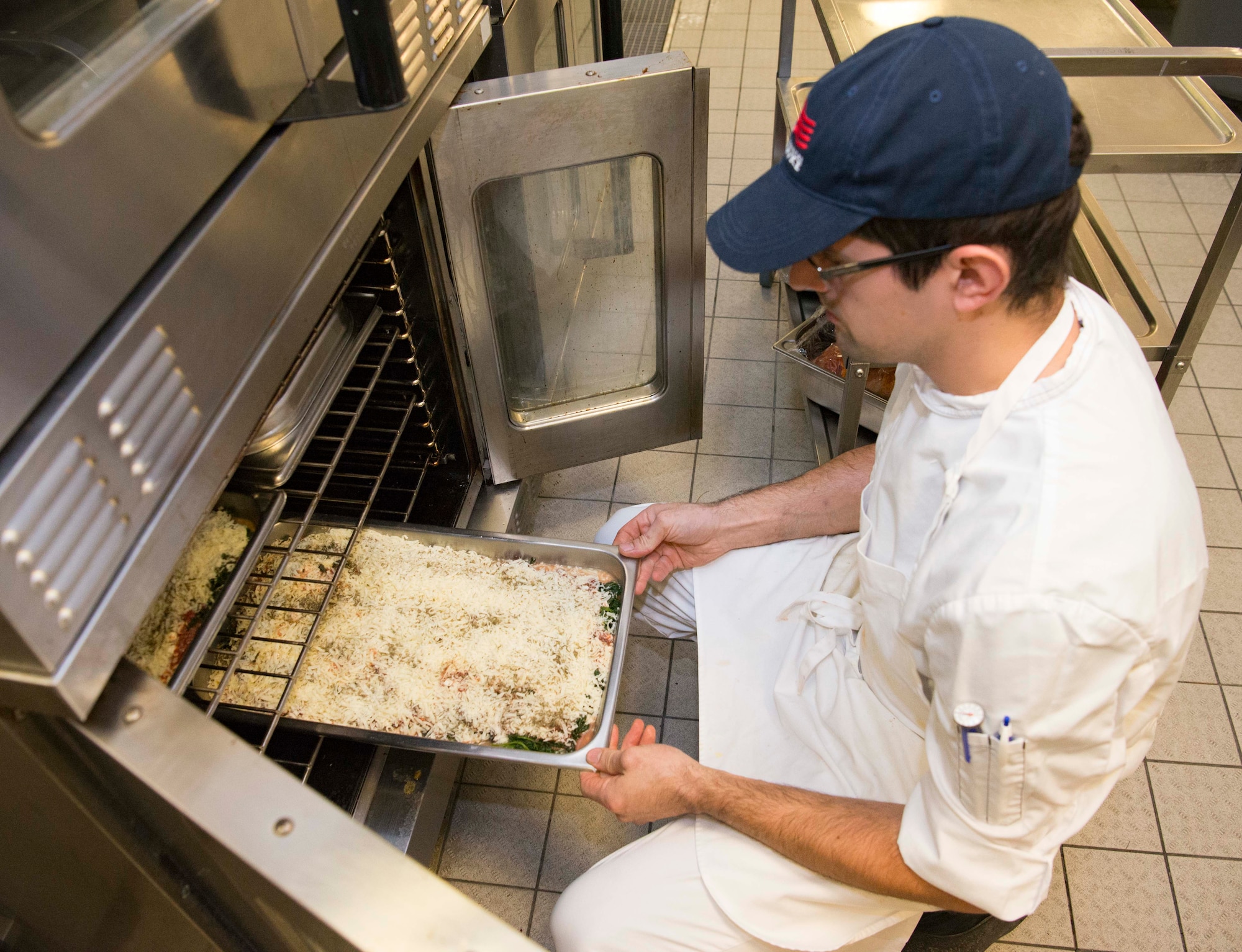 Carsten Mueller, 786th Force Support Squadron Rheinland Inn lead cook, puts lasagna in the oven on Ramstein Air Base, Germany, Nov. 3, 2017. The Rheinland Inn mission is to provide nutritious, flavorful and quality meals for dormitory residents. (U.S. Air Force photo by Senior Airman Elizabeth Baker)