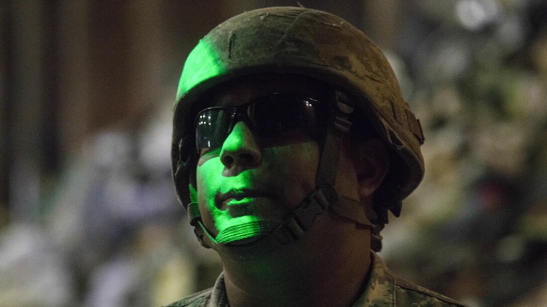 A soldier stands in green light.