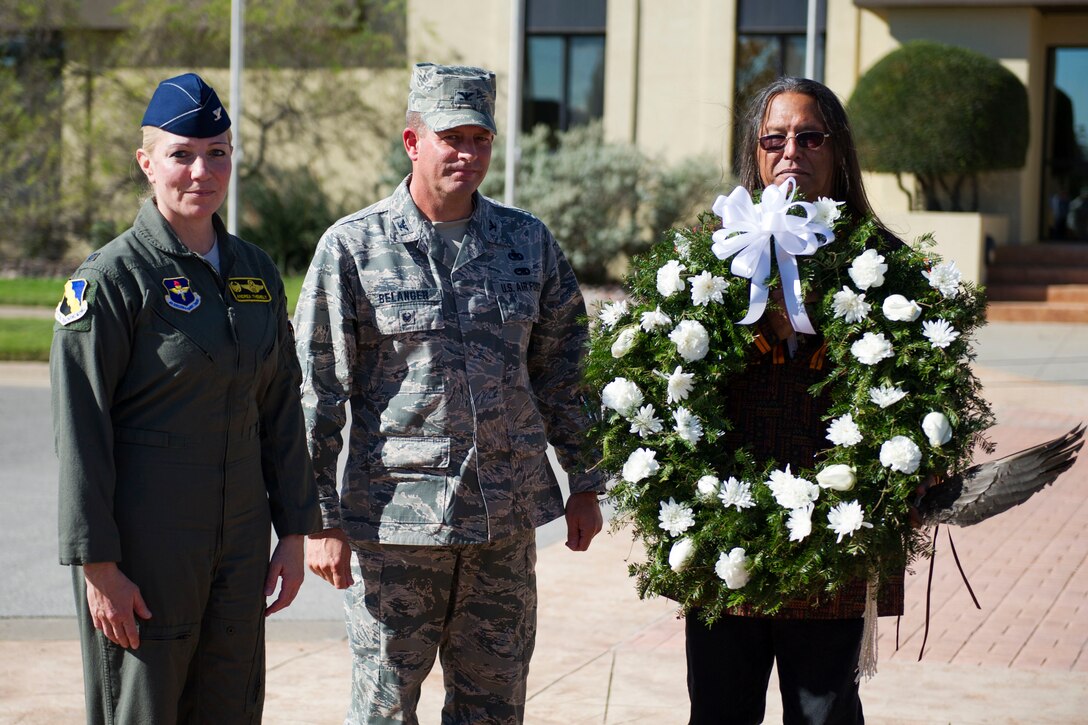 Three people hold a wreath.