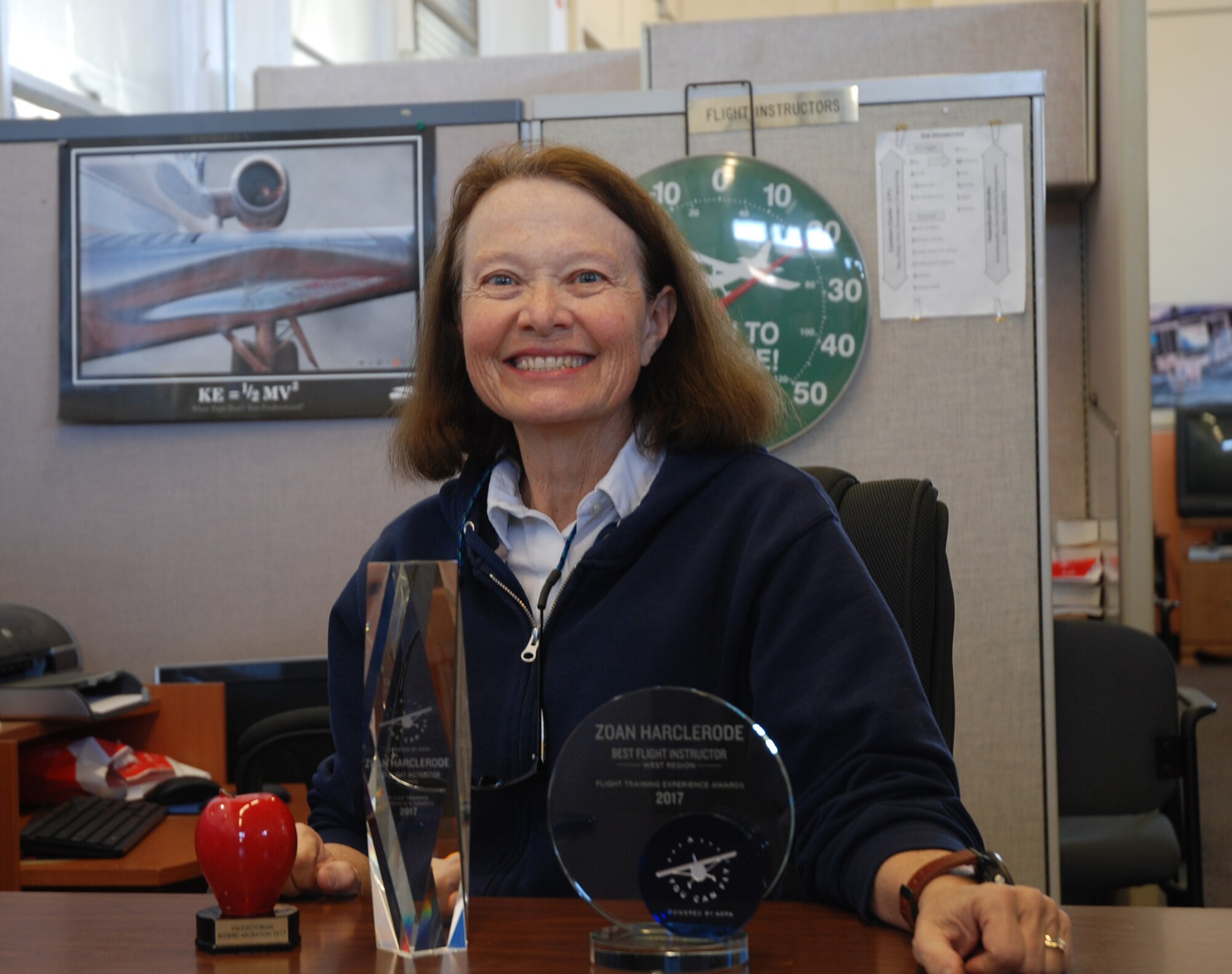 Zoan Harclerode, flight instructor at the Rocky Mountain Flight Training Center on Peterson Air Force Base, Colorado, poses at her desk with her Westeren Region and National Pilot of the Year awards Oct. 31, 2017. The Aircraft Owners and Pilots Association recognized her from among 2,012 nominated pilots.  (U.S. Air Force photo by Dave Smith)