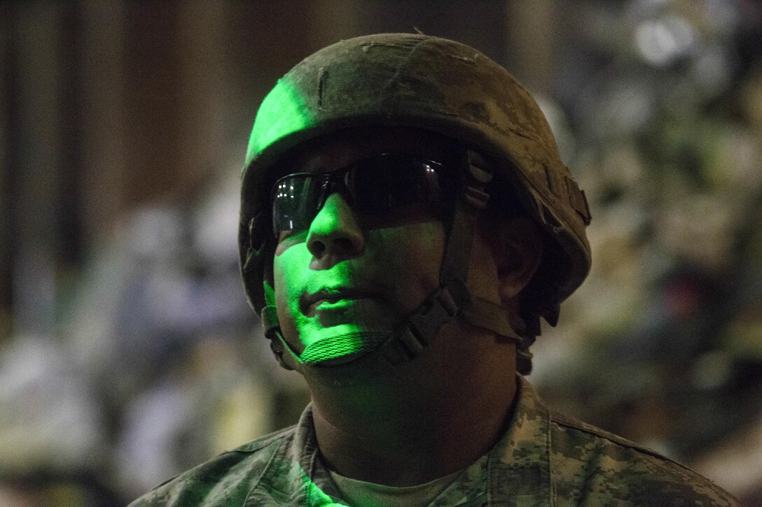 A soldier stands in green light.