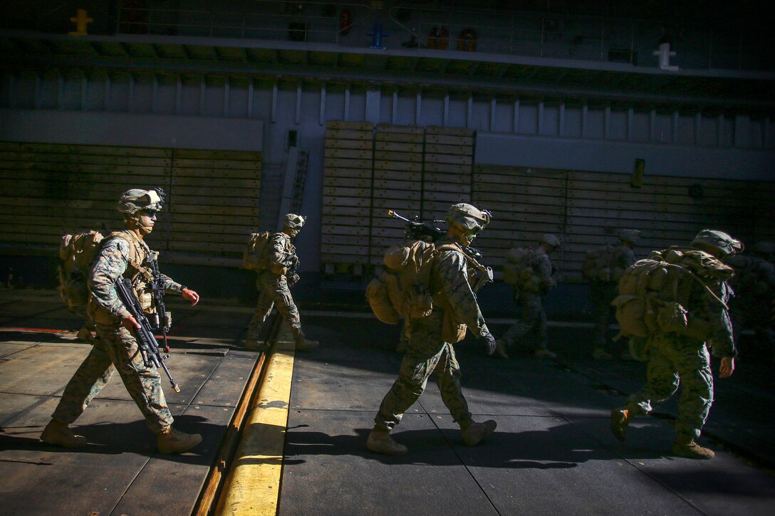Marines walk along the well deck of the USS Ashland before participating in an amphibious landing during Blue Chromite 18.