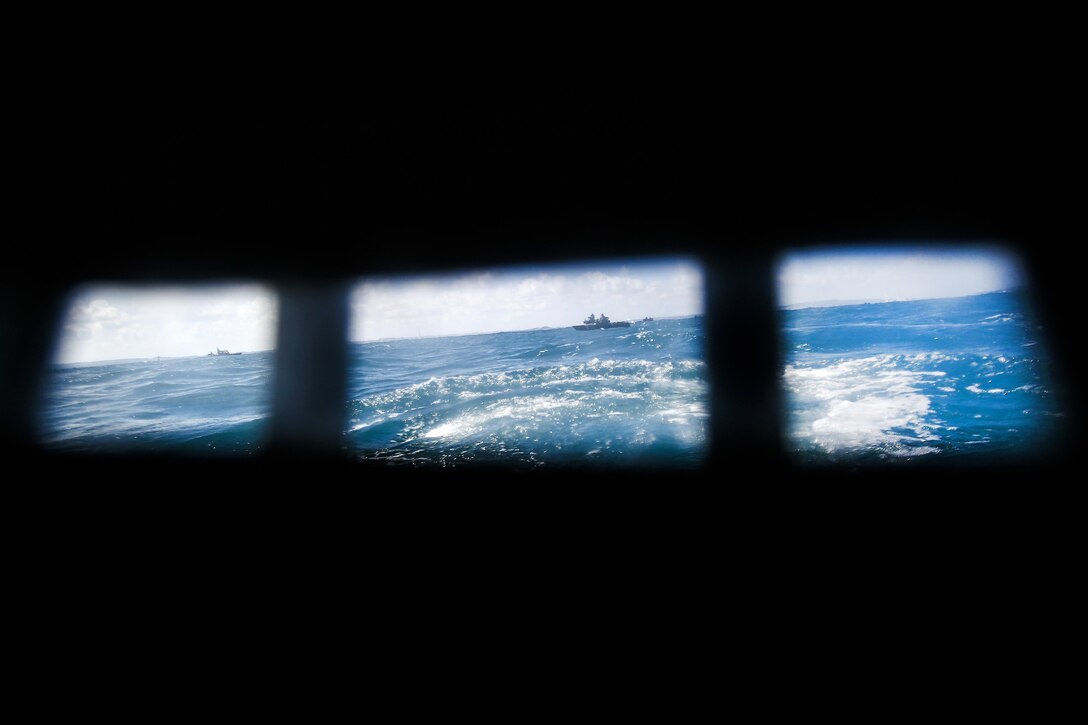 Amphibious Assault Vehicles can be seen in the distance through the back of an AAV window slot during exercise Blue Chromite 18.