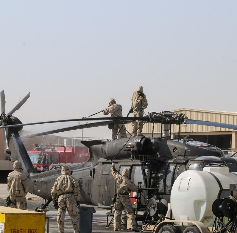 Soldiers decontaminating a helicopter.