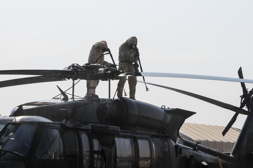 Two soldiers decontaminate a helicopter.