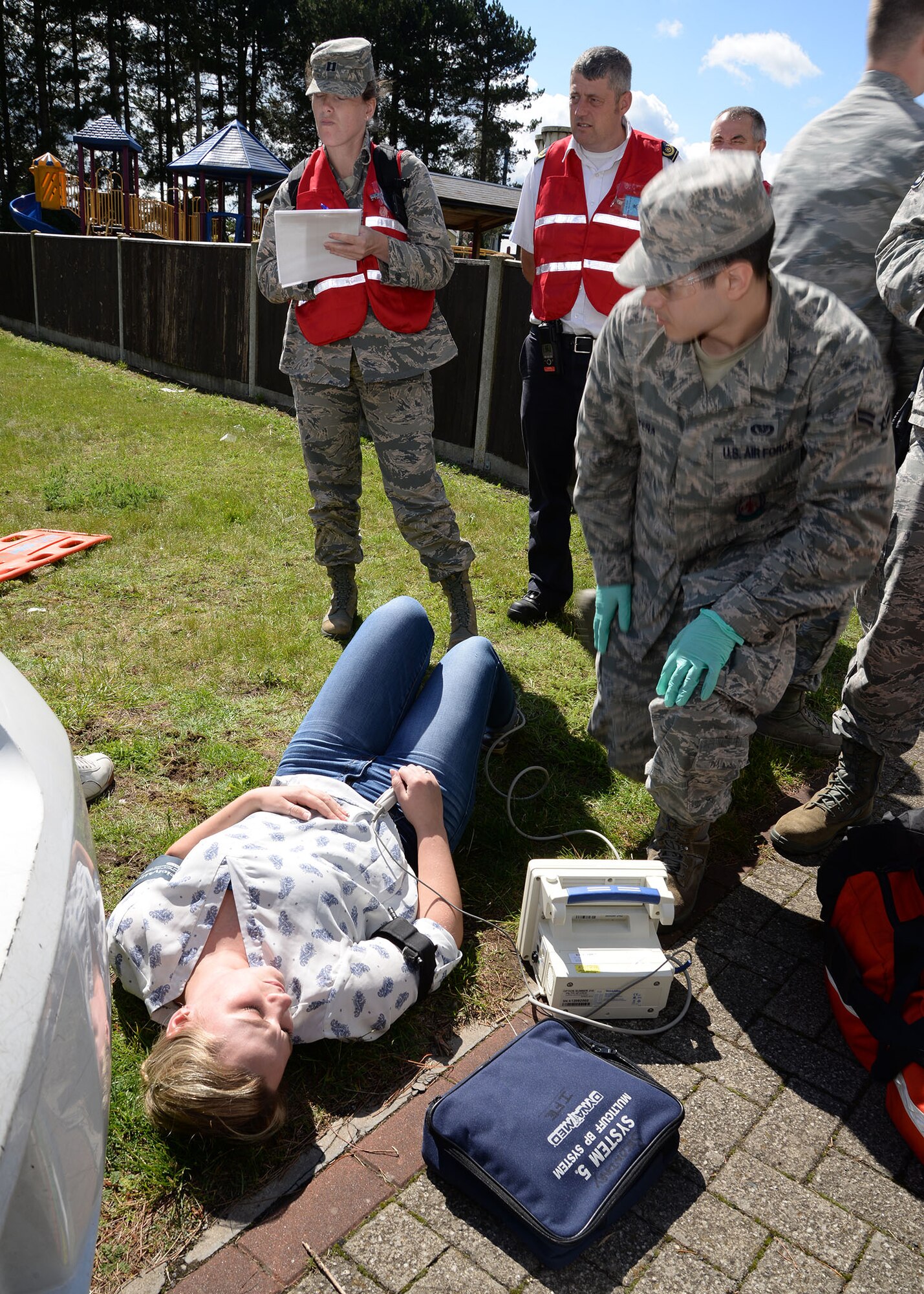 Members of the 100th Air Refueling Wing inspection team, wearing red vests, evaluate the response from emergency services during an active shooter exercise Aug. 17, 2017, on RAF Mildenhall, England. Subject matter experts from a variety of agencies around base form the wing inspection team, and in addition to planning exercise scenarios with members of the 100th ARW Inspector General office, evaluate a variety of responses to each part of the exercise in order to enhance readiness. (U.S. Air Force photo by Karen Abeyasekere)