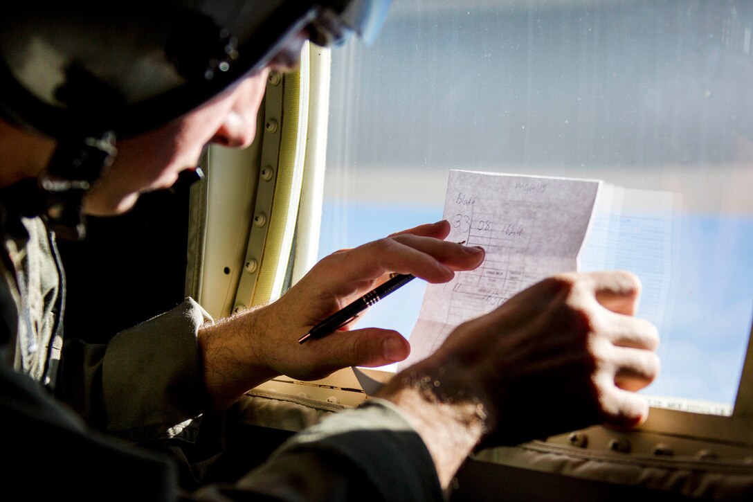A Marine writes a note on paper placed against an aircraft window.