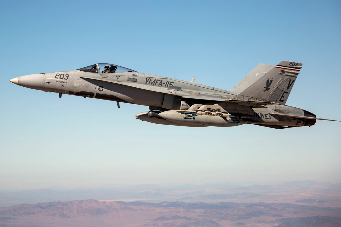 An F/A-18C Hornet flies through blue skies.